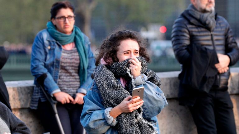 A woman reacts as she watches the flames engulf the roof of the Notre-Dame Cathedral in Paris 