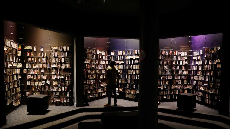 A visitor looks at an exhibition displaying pictures of victims at the Genocide Memorial in Gisoz