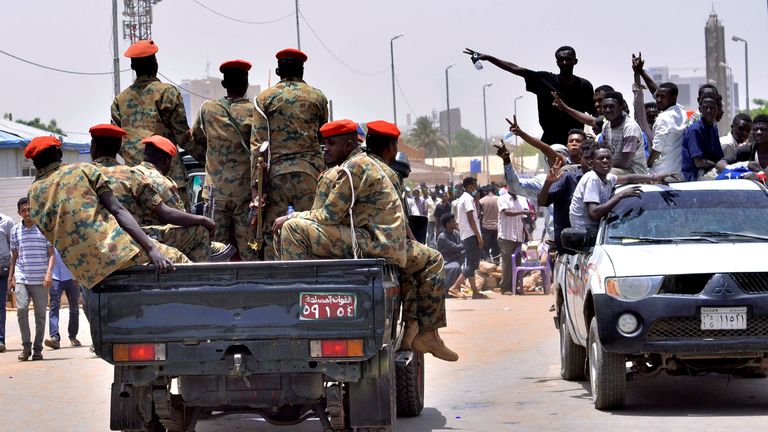Sudanese demonstrators drive towards a military vehicle