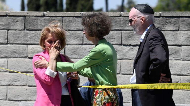 Synagogue members console one another outside of the Chabad of Poway Synagogue