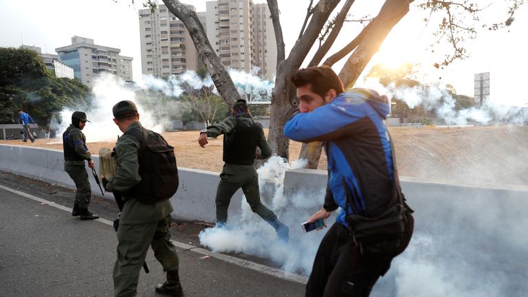 Military members react to tear gas, near the Generalisimo Francisco de Miranda Airbase "La Carlota", in Caracas, Venezuela