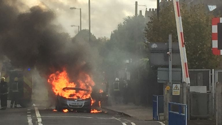 Firefighters extinguish a Vauxhall Zafira which caught light in Manor Road, southwest London

