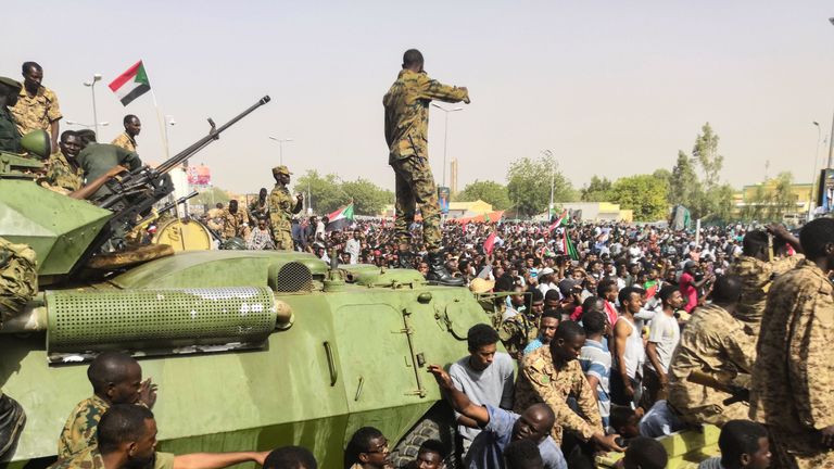 Sudanese soldiers stand guard on armoured military vehicles in the capital Khartoum