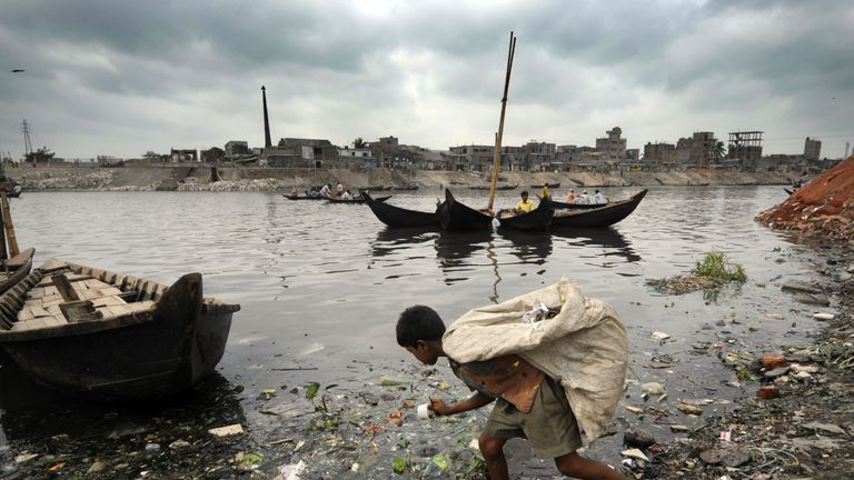 A Bangladeshi child collects garbage from the litter-strewn river bank in Dhaka
