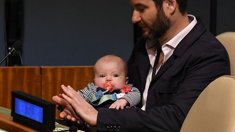 Clarke Gayford (C) claps holding his daughter Neve Te Aroha Ardern Gayford, as his partner Jacinda Ardern, Prime Minister and Minister for Arts, Culture and Heritage, and National Security and Intelligence of New Zealand speaks during the Nelson Mandela Peace Summit September 24, 2018, one day before the start of the General Debate of the 73rd session of the General Assembly at the United Nations in New York
