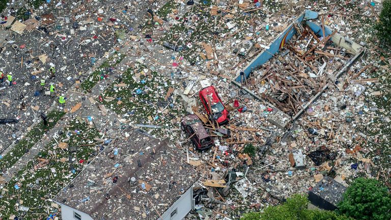 Damaged vehicles next to the debris of the home explosion