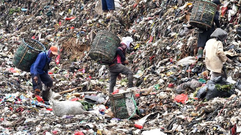 This picture taken on May 23, 2018 shows Indonesian rubbish pickers sifting through a mountain of garbage with their bare hands, at the Bantar Gebang landfill, in the city of Bekasi on the outskirts of the Indonesian capital. 