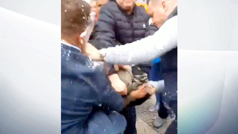 Tommy Robinson (L) is filmed punching the man four times. Pic: @SianyJx
