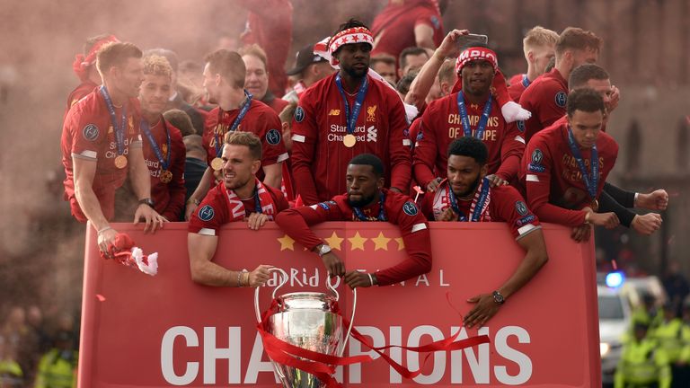 Liverpool's English midfielder Jordan Henderson and Liverpool's Dutch midfielder Georginio Wijnaldum hold the European Champion Clubs' Cup trophy, with teammates Liverpool's English midfielder James Milner, Liverpool's English midfielder Alex Oxlade-Chamberlain, Liverpool's Belgian striker Divock Origi, Liverpool's English striker Daniel Sturridge Liverpool's English defender Joe Gomez and Liverpool's English defender Trent Alexander-Arnold during an open-top bus parade around Liverpool, north-west England on June 2, 2019, after winning the UEFA Champions League final football match between Liverpool and Tottenham. - Liverpool's celebrations stretched long into the night after they became six-time European champions with goals from Mohamed Salah and Divock Origi to beat Tottenham -- and the party was set to move to England on Sunday where tens of thousands of fans awaited the team's return. The 2-0 win in the sweltering Metropolitano Stadium delivered a first trophy in seven years for Liverpool, and -- finally -- a first win in seven finals for coach Jurgen Klopp. (Photo by Oli SCARFF / AFP) (Photo credit should read OLI SCARFF/AFP/Getty Images)