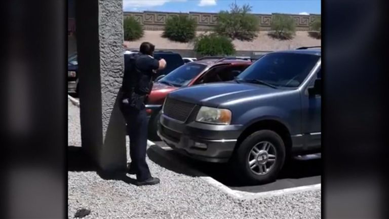 An officer appears to point a weapon at the vehicle, which contains Ms Harper and her two children