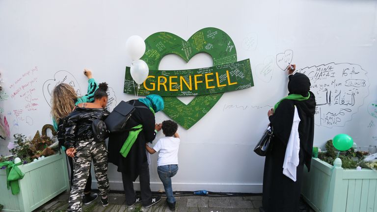 Family and friends of the 72 people who lost their lives in the fire write messages on a memorial wall