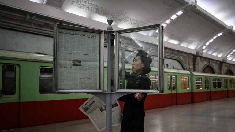 A train conductor changes a newspaper as she updates a newsstand in a subway station in Pyongyang on June 19, 2019, ahead of a visit to the North Korean capital by Chinese President Xi Jinping on June 20