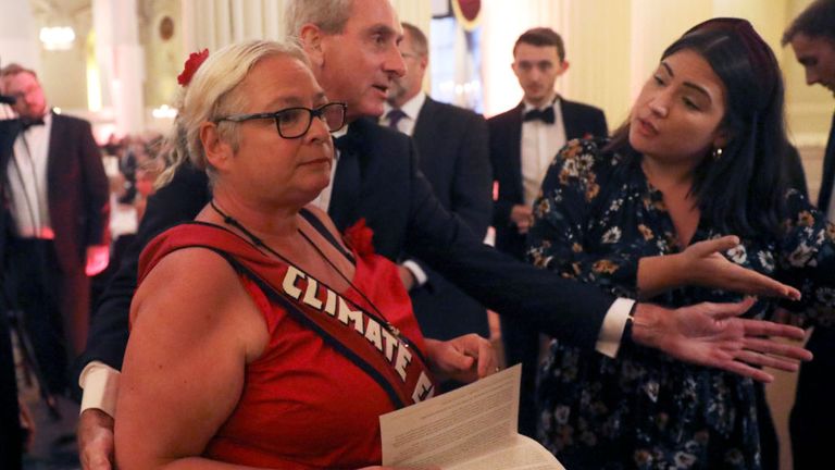 LONDON, ENGLAND - JUNE 20: Climate change protester is escorted out after interrupting British Chancellor of the Exchequer Philip Hammond&#39;s speech during the annual Mansion House dinner on June 20, 2019, in London, England. Greenpeace volunteers wearing red evening dress with sashes reading "climate emergency" gatecrashed and disrupted the beginning of Chancellor Philip Hammond&#39;s Mansion House speech. (Simon Dawson - WPA Pool/Getty Images)