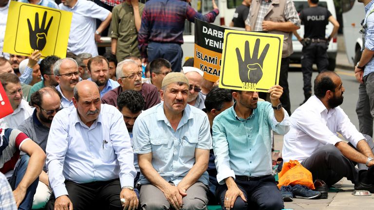 People holds placard depicting the symbol "Rabaa" of the supporters of  Mohamed Morsi in Ankara