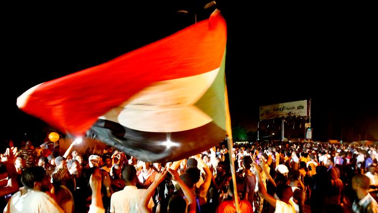 People wave flags and chant slogans outside army headquarters