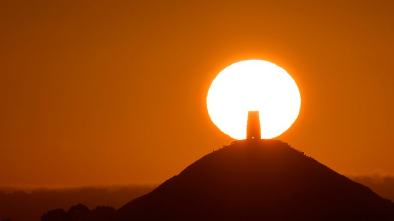 Revellers celebrate the Summer Solstice as the sun rises at Glastonbury Tor