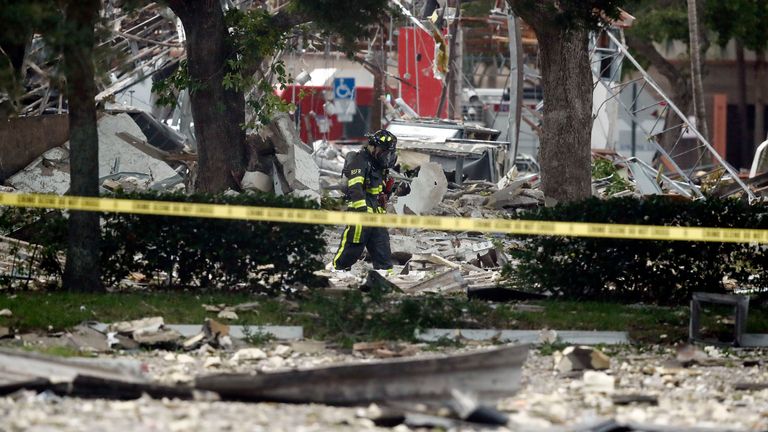 A firefighter walks through the remains of a building after an explosion on Saturday, July 6, 2019, in Plantation, Fla. Several people were injured after a vacant pizza restaurant exploded in the South Florida shopping plaza Saturday, according to police. The restaurant was destroyed, and nearby businesses were damaged. (AP Photo/Brynn Anderson)