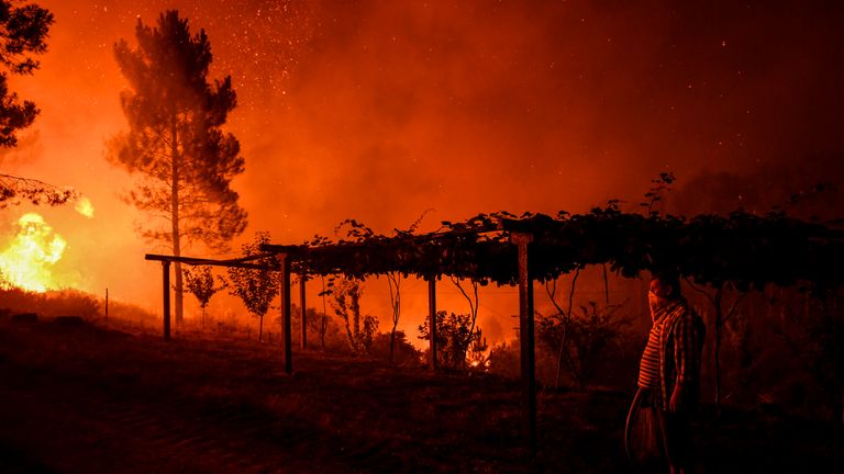 A villages holds a hose as a wildfire comes close to his house at Amendoa in Macao, central Portugal on July 21, 2019. - More than a thousand firefighters battled to control wildfires in central Portugal that have forced village evacuations, in a region where dozens were killed in huge blazes in 2017. The firefighters were deployed to tackle three fires in the mountainous and heavily forested Castelo Branco region, 200 kilometres north of Lisbon, according to the website of the Civil Protection. (Photo by PATRICIA DE MELO MOREIRA / AFP)        (Photo credit should read PATRICIA DE MELO MOREIRA/AFP/Getty Images)