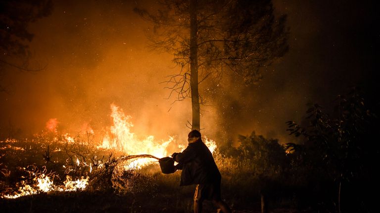 A villager tries to put out the fire as it gets close to his house at Amendoa in Macao, central Portugal on July 21, 2019. - More than a thousand firefighters battled to control wildfires in central Portugal that have forced village evacuations, in a region where dozens were killed in huge blazes in 2017. The firefighters were deployed to tackle three fires in the mountainous and heavily forested Castelo Branco region, 200 kilometres north of Lisbon, according to the website of the Civil Protection. (Photo by PATRICIA DE MELO MOREIRA / AFP)        (Photo credit should read PATRICIA DE MELO MOREIRA/AFP/Getty Images)