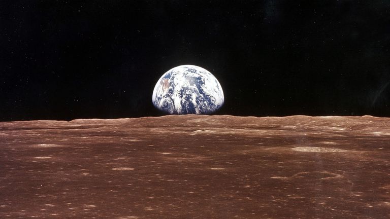 A view of the Earth appears over the Lunar horizon as the Apollo 11 Command Module comes into view of the Moon before Astronauts Neil Armstrong and Edwin Aldrin Jr. leave in the Lunar Module, Eagle, to become the first men to walk on the Moon&#39;s surface