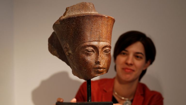 Laetitia Delaloye, head of antiquities of Christie's, poses for a photograph with an Egyptian brown quartzite head of Tutankhamen prior to its sale at Christie's auction house in London on Thursday