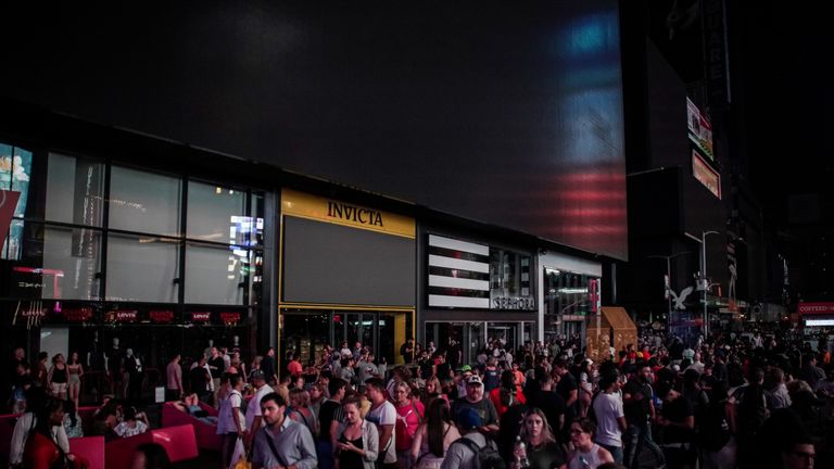 People walk along a dark street near Times Square area, as a blackout affects buildings and traffic during widespread power outages in the Manhattan borough of New York, U.S, July 13, 2019