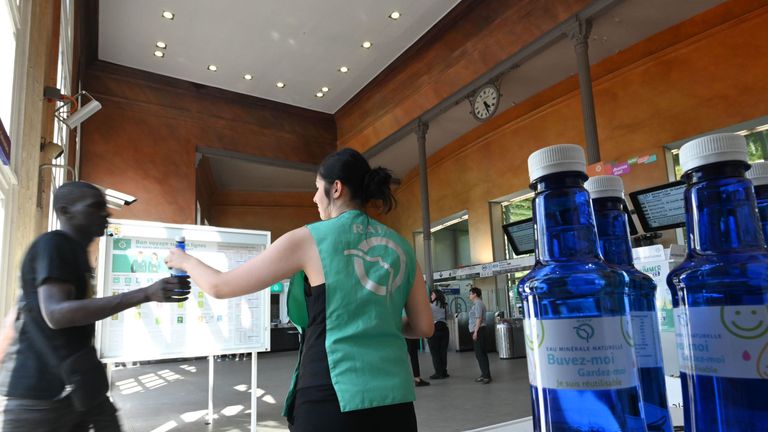 An agent of the RATP (Autonomous Operator of Parisian Transports) distributes bottles of water to commuters in Paris on July 23, 2019