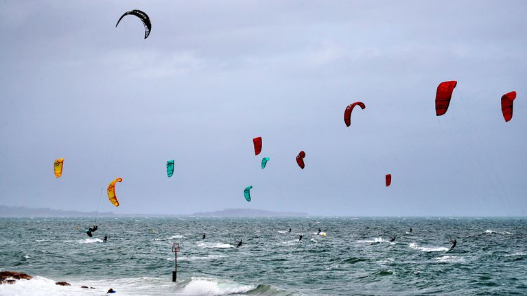 Kite surfers enjoy the strong winds off of Branksome Chine, near Poole in Dorset. Warnings for rain and wind came into force across nearly all of the UK today.