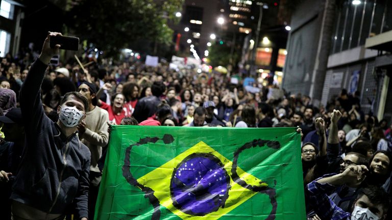 Protesters hold a Brazilian flag with the letters SOS written on it during a demonstration to demand for more protection for the Amazon rainforest, in Sao Paulo, Brazil, August 23, 2019