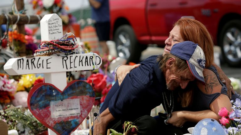 Antonio Basco, whose wife Margie Reckard was murdered during a shooting at a Walmart store, is comforted by a woman next to a white wooden cross bearing the name of his late wife, at a memorial for the victims of the shooting in El Paso, Texas, U.S. August 15, 2019. REUTERS/Jose Luis Gonzalez TPX IMAGES OF THE DAY