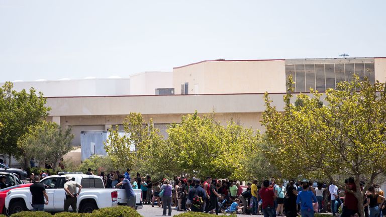 People that were evacuated sit in a parking lot across from a Walmart where a shooting occurred at Cielo Vista Mall