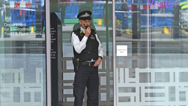 A police officer in the doorway of a government building in Marsham Street in Westminster after an incident in which a man was stabbed