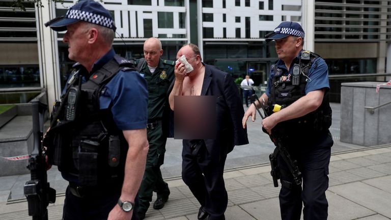 An injured man is helped by a medic and police officers outside the Home Office in London