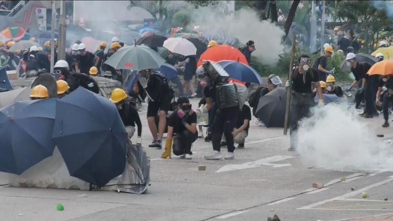 Protesters move behind umbrellas as tear gas flies on the streets of Hong Kong