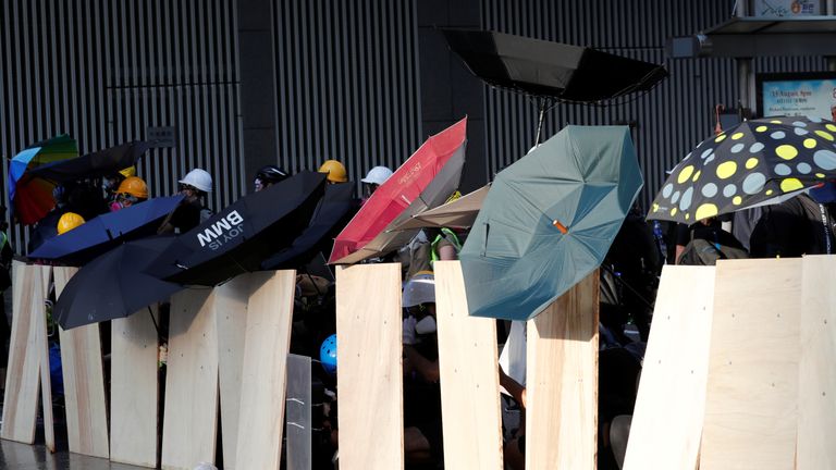 Protesters use umbrellas as they form a barricade