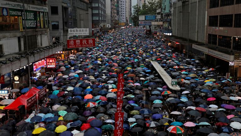 People with umbrellas up filling a street in Hong Kong