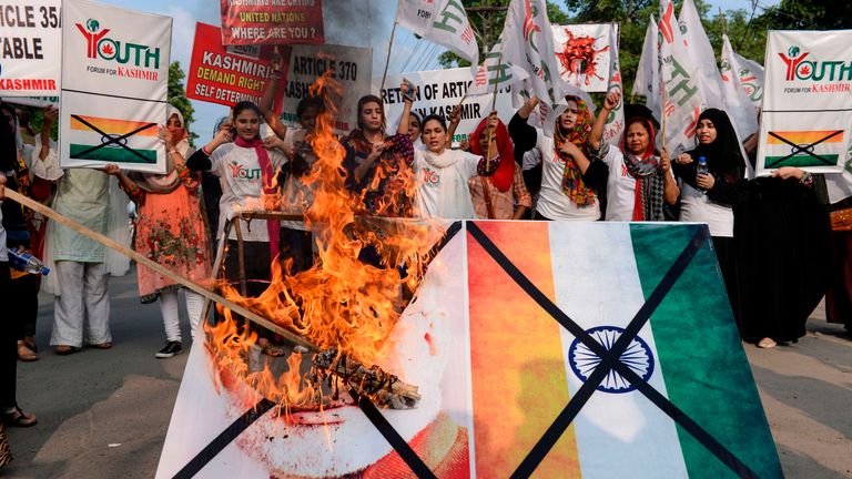 Protesters in Lahore, Pakistan, burn a picture of Modi and the Indian flag