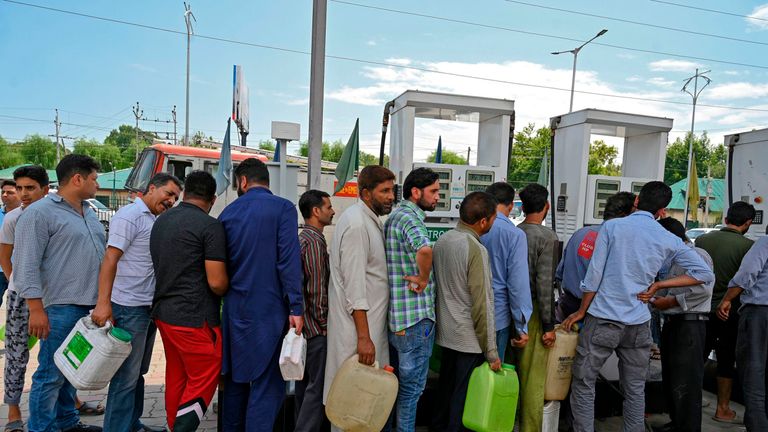 Kashmiri people stand in a queue at a petrol station in Srinagar 