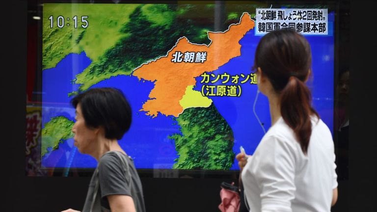 Pedestrians in Japan walk past a roadside television screen reporting on North Korea's projectile launch 