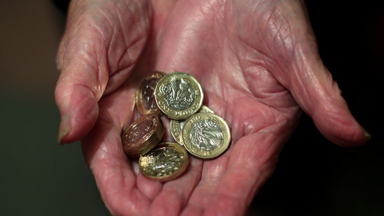 An elderly woman holding pound coins in her hands in Poole, Dorset.                                                                                                             