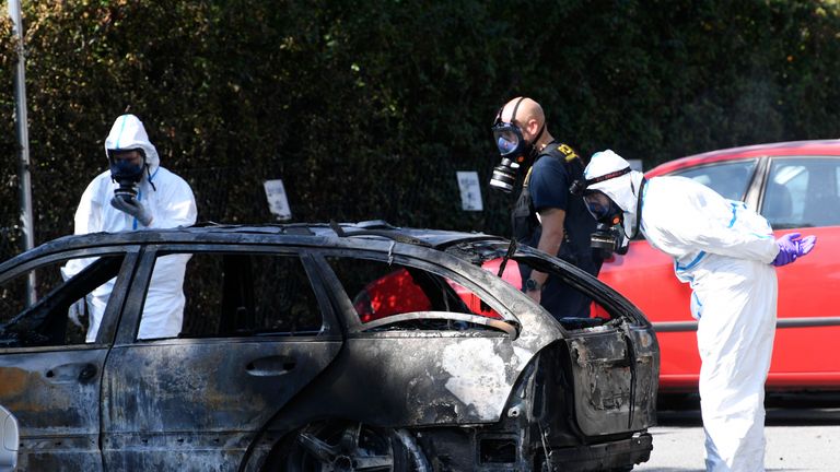 Forensic officers inspected a burned out car nearby after the woman was killed