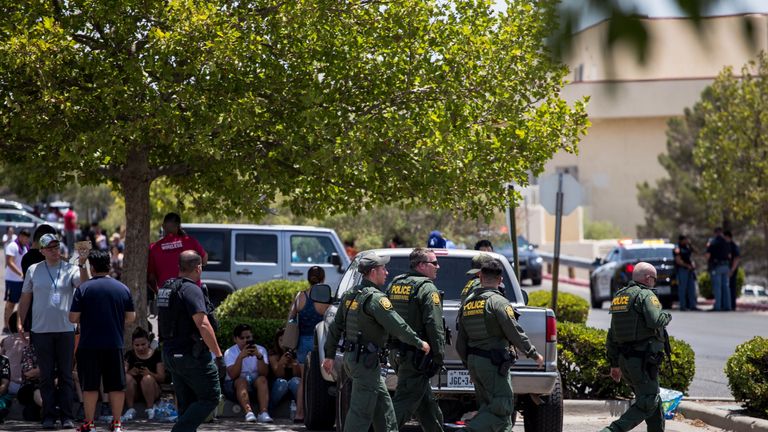 Customs and Border Patrol police walk past individuals that were evacuated from Cielo Vista Mall 