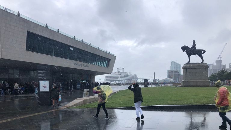 Tourists battle against wind and rain at Pier Head in Liverpool