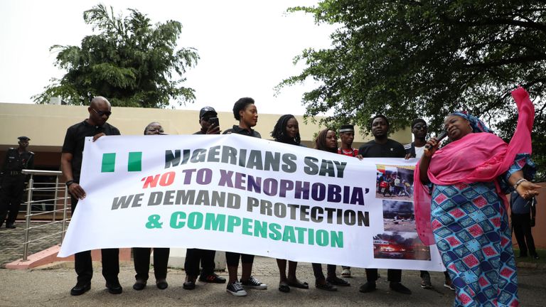 People stand behind a banner a protest against xenophobia outside of the main gate of the South African High Commission which was shut down to avert reprisal attacks in Abuja, on September 5, 2019. - South Africa said on September 5, 2019 it had temporarily closed its diplomatic missions in Nigeria following violence against South African businesses carried out in reprisal for attacks on foreign-owned stores in Johannesburg. (Photo by KOLA SULAIMON / AFP)        (Photo credit should read KOLA SULAIMON/AFP/Getty Images)