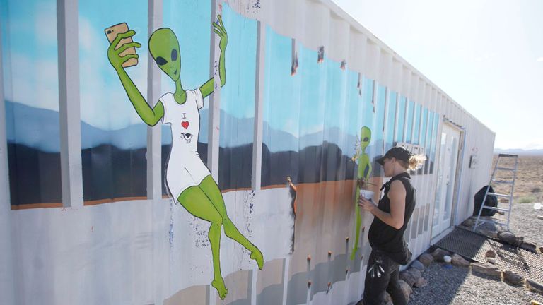 An artist paints the side of a building near the Storm Area 51 event this weekend