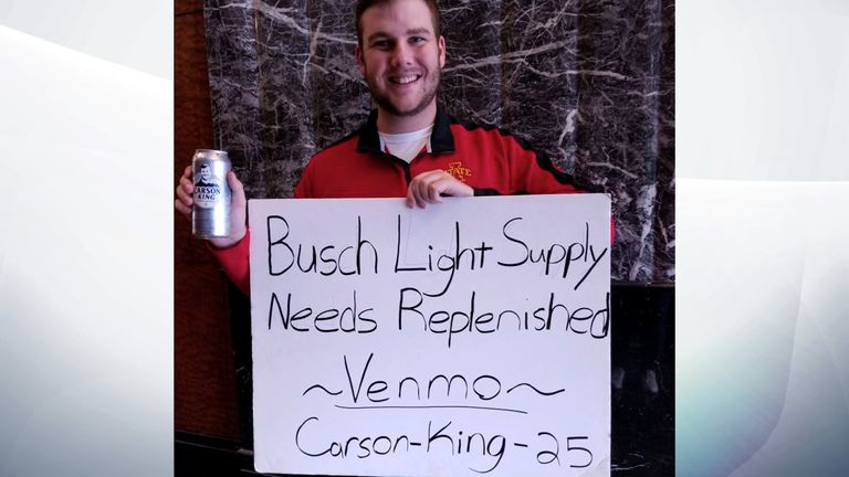 Carson King poses with his sign and a beer with his face on. Pic: Carson King