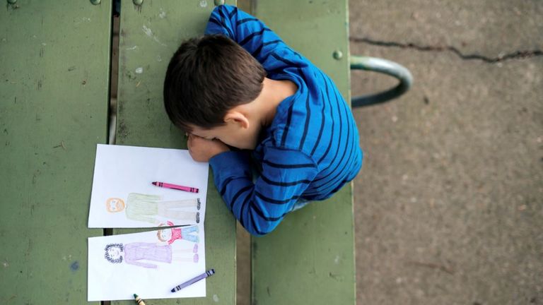 Young boy looking sad at drawing of a broken family