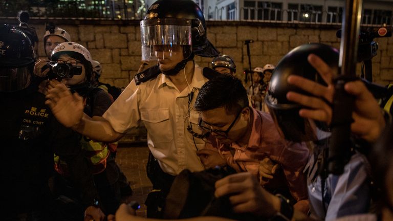 Police officers help a man who was taunted by protesters after claiming he was a Chinese tourist