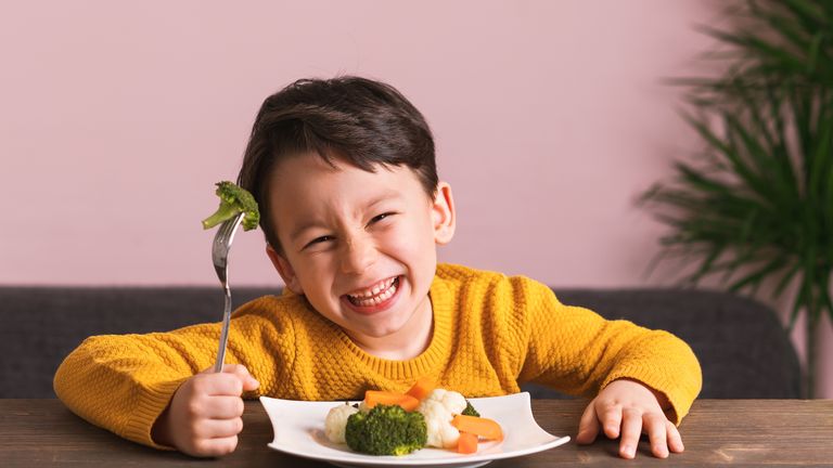 Child is eating vegetables. He is very happy.