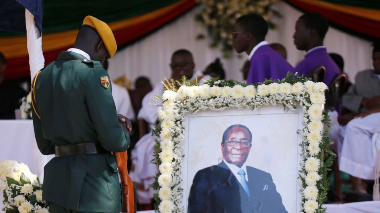 A soldier stands beside a picture of former Zimbabwean President Robert Mugabe during a church service at his rural village in Kutama, Zimbabwe, September 28, 2019